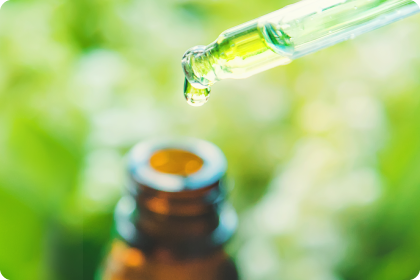 Pipette tropft in Flasche vor Grünen verwaschenen Hintergrund