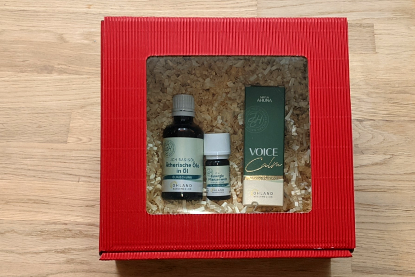 Rote Geschenkbox mit Fenster und Dekopapier auf dem 3 Produkte Liegen