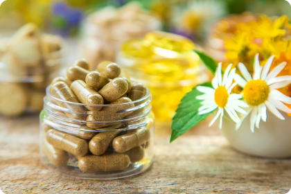 Kapseln im Glas auf deinen Tisch mit rechts blumen in Weiß, Gelb und Orange